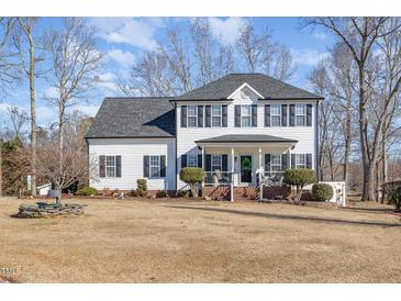 Charming two-story home featuring a covered porch, black shutters and mature landscaping at 761 Raymond Dr, Clayton, NC 27527