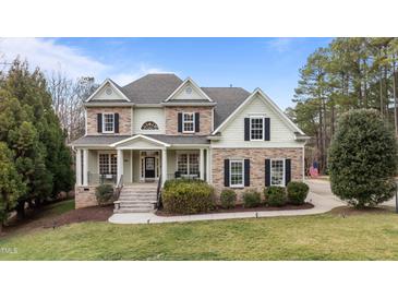 Charming two-story home with stone accents, a welcoming front porch, and professionally landscaped yard at 7709 Moondance Ct, Wake Forest, NC 27587