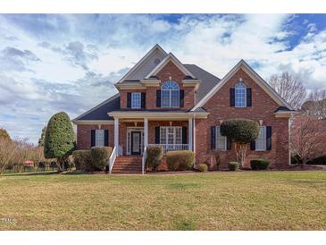 Stunning brick home featuring a manicured lawn, black shutters and a welcoming front porch at 9041 Chelsea Dr, Raleigh, NC 27603