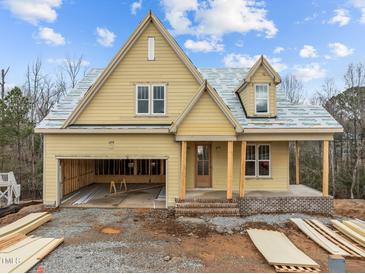 Charming home under construction featuring yellow siding, a welcoming porch, and a convenient attached garage at 108 Pointe Park Cir, Holly Springs, NC 27540