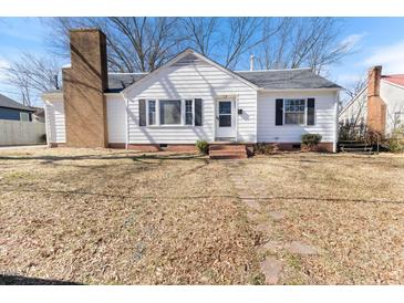 Charming white home featuring black shutters, brick chimney, and well-manicured front yard at 307 Gordon St, Roxboro, NC 27573