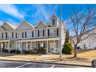 Charming townhome featuring a covered front porch, neutral siding, and black shutters, set against a bright blue sky at 3931 Volkswalk Pl, Raleigh, NC 27610
