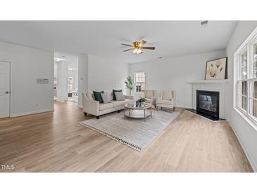 Bright living room features a fireplace, ceiling fan, and wood flooring, providing a warm and inviting atmosphere at 4207 Hampstead Village Dr, Durham, NC 27703