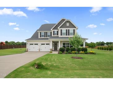 Charming two-story home with a well-manicured lawn, a three-car garage, and beautiful landscaping at 6804 Arlington Oaks Trl, Raleigh, NC 27603