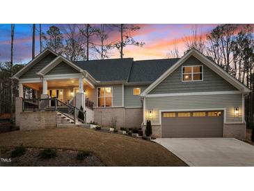 Charming home with a brick foundation, two-car garage, and beautiful landscaping at sunset at 112 Rawhide Dr, Louisburg, NC 27549