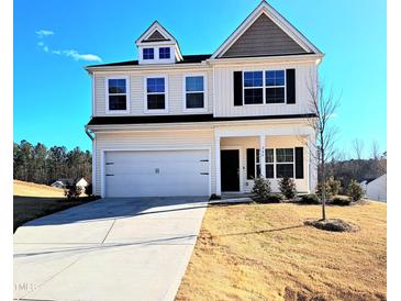 Charming two-story home with a two car garage and a well-manicured lawn under a clear blue sky at 265 Forest Meadow Ln, Franklinton, NC 27525