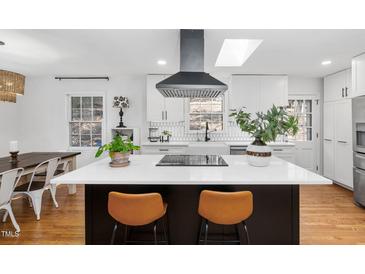 Bright kitchen features a large island with seating, modern appliances, and an eye-catching range hood at 330 Wesley Dr, Chapel Hill, NC 27516