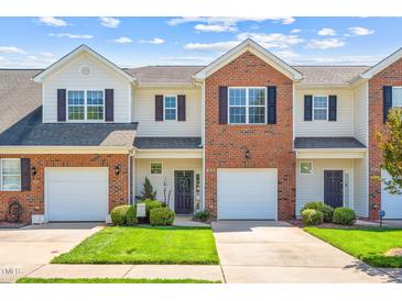 Charming townhouse with brick and siding exterior, well-maintained lawn, and attached garage on a sunny day at 622 Village Lake Drive, Mebane, NC 27302