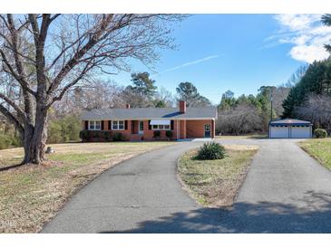 Charming brick home with a well-maintained lawn, a long driveway, and a detached garage at 8604 N Roxboro St, Bahama, NC 27503