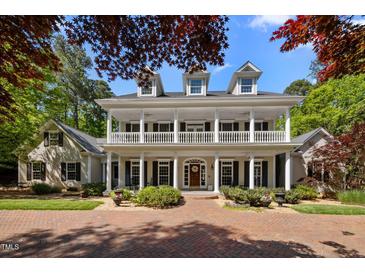 Stately home with a large front porch, dormer windows, and a well-manicured lawn and circular brick driveway at 109 Chimeneas Pl, Chapel Hill, NC 27517