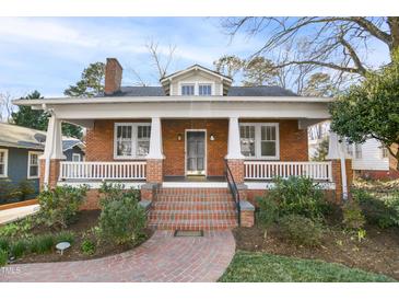 Charming brick home featuring a welcoming front porch, landscaped yard, and classic architectural details at 2005 Glenwood Ave, Raleigh, NC 27608