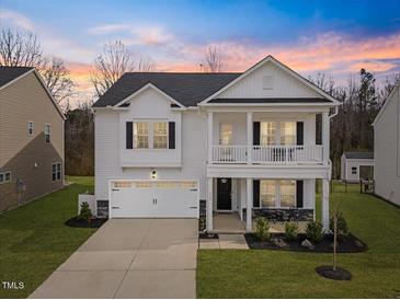 Charming two-story home featuring a welcoming front porch and attached garage with a beautiful sunset backdrop at 213 Chateau Way, Angier, NC 27501