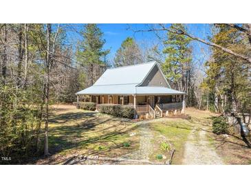 Inviting home with a charming front porch, mature trees, and natural landscaping at 348 Raymond Tharrington Rd, Louisburg, NC 27549