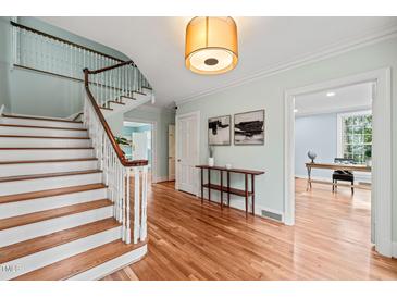 Bright foyer with hardwood floors, white trim, light blue walls, and a staircase at 422 Westwood Dr, Chapel Hill, NC 27516