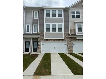 Modern townhome featuring a two-car garage, stone accents, and gray siding at 5322 River Reach Dr, Raleigh, NC 27616