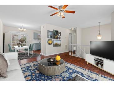 Cozy living room featuring hardwood floors, ceiling fan, and adjacent dining area with a modern table set at 7 Harrigan Ct, Durham, NC 27705