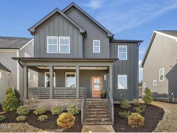 Charming two-story home with a welcoming front porch, landscaped yard, and stylish dark gray siding at 705 Vine Pkwy, Pittsboro, NC 27312
