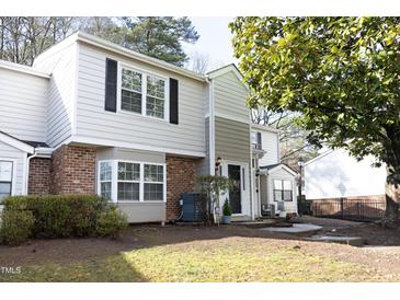 Charming townhome featuring a brick facade, large windows, and manicured landscaping at 7736 Falcon Rest Cir, Raleigh, NC 27615