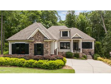 Charming home featuring stone accents, neutral siding, black shutters, and a well-manicured lawn at 946 Berry Patch Ln, Pittsboro, NC 27312