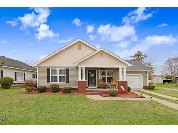 Charming home featuring a cozy front porch with rocking chairs, a well-manicured lawn, and delightful curb appeal at 112 E Main St, Micro, NC 27555