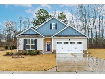Charming single-Gathering home featuring a two-car garage, blue accents and a well-manicured lawn at 120 Longspur Ln, Rolesville, NC 27571