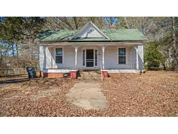 Charming single-story home featuring a covered front porch, set against a backdrop of mature trees at 404 Cherry St, Oxford, NC 27565