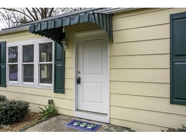 Charming home entrance featuring a white door, matching trim, and complementary green awning and shutters at 510 Short W St, Hillsborough, NC 27278