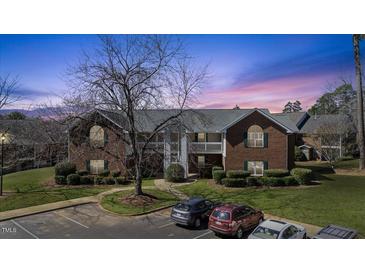 Brick apartment complex with a manicured lawn and ample parking at dusk at 723 Renshaw Ct, Cary, NC 27518