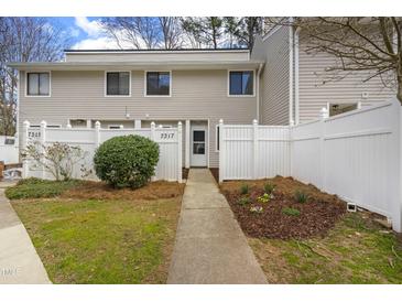Charming townhouse with a white fence, walkway, and manicured landscaping at 7317 Sandy Creek Dr, Raleigh, NC 27615
