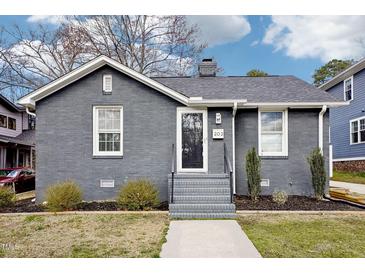Charming single story brick home with manicured lawn, walkway, and front door at 202 W Lavender Ave, Durham, NC 27704