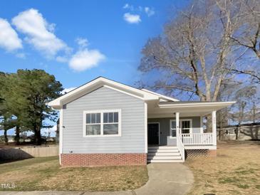 Charming single-story home with blue siding, red brick accents, and a cozy front porch at 265 Freeman Pines Pl, Fuquay Varina, NC 27526