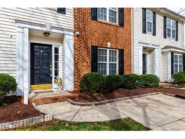 Inviting townhome entrance featuring a black front door, manicured landscaping, and a brick facade at 3122 Coxindale Dr, Raleigh, NC 27615