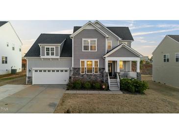Charming two-story home featuring gray siding, stone accents, and a welcoming front porch with manicured landscaping at 363 Grey Hawk Dr, Garner, NC 27529