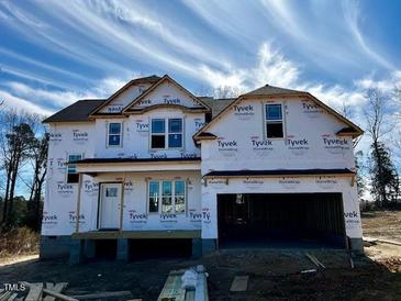 Under construction home featuring a two-car garage and a classic two-story design covered with Tyvek HomeWrap at 48 Golden View Pl, Zebulon, NC 27597