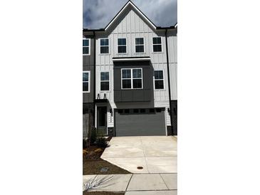 Modern townhome featuring a two-car garage and neutral-tone exterior with black trim and visible house number at 1005 Regalia Rd # 32, Durham, NC 27713