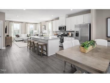Open-concept kitchen features a large island with seating and stainless steel appliances, flowing into a cozy living area at 1364 Chowan Ave, Durham, NC 27713