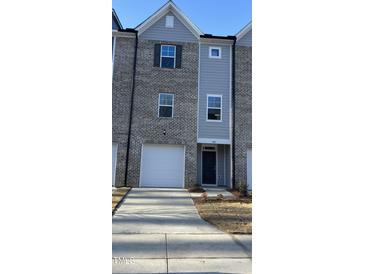 Charming townhome exterior features a one car garage and a gray brick and siding facade at 1913 Fishamble St, Fuquay Varina, NC 27526