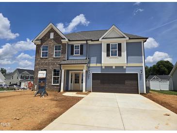 Two-story home featuring blue siding, brick accents, a two-car garage, and a well-manicured lawn at 2102 Channel St, Graham, NC 27253