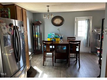 A dining room features wood-look flooring, wood table and chairs, and a stainless steel refrigerator at 402 Todd Hill Dr, Wendell, NC 27591