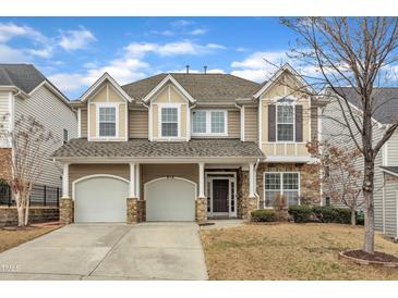 Charming two-story home showcasing a manicured lawn, attached two-car garage, and stone detailing at 413 Westfalen Dr, Cary, NC 27519
