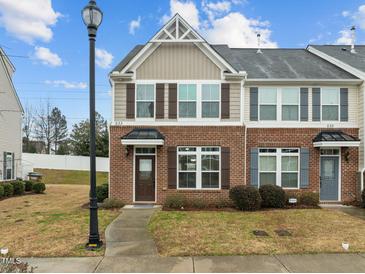 Charming two-story townhouse featuring a brick facade, decorative shutters, and a well-manicured lawn at 533 Berry Chase Way, Cary, NC 27519