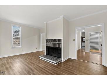Bright living room with wood floors, fireplace and large window at 5738 Sentinel Dr, Raleigh, NC 27609