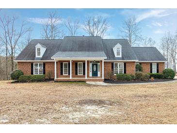Charming brick home features a well-manicured lawn and welcoming front porch with columns at 8724 Ten Ten Rd, Raleigh, NC 27603