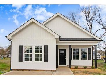 Charming single-story home featuring white siding, black shutters, and a welcoming front porch at 1021 E Edgerton St, Dunn, NC 28334