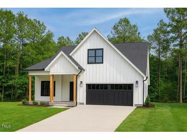 New home with a modern farmhouse design, black garage door, a manicured lawn, and black trim windows at 148 Mohawk Dr, Louisburg, NC 27549