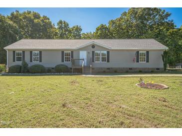 Charming single-story home with a well-manicured lawn, complemented by mature trees and an American flag at 7850 Nc 42, Holly Springs, NC 27540
