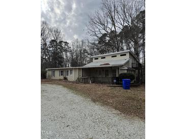 Two-story home with porch, deck and gravel driveway, surrounded by trees at 731 Latimer St, Hillsborough, NC 27278