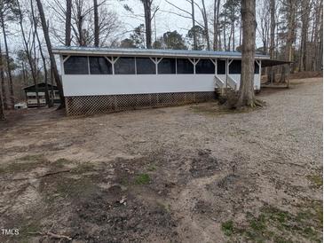 Single-story home with a long, screened-in porch and neutral exterior, surrounded by trees at 122 Tomahawk Dr, Louisburg, NC 27549