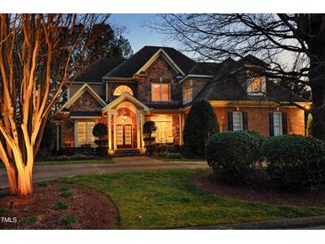 Stunning two-story home featuring stone and brick facade, manicured lawn, and welcoming front porch with a double-door entryway at 12417 Richmond Run Dr, Raleigh, NC 27614