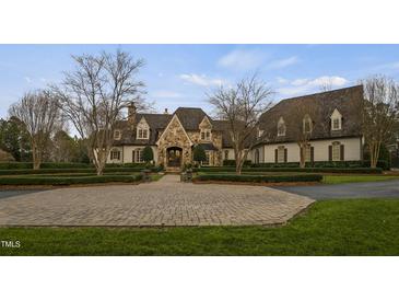 Stately stone and white brick home with mature landscaping and circular driveway at 266 Perfect Moment Dr, Durham, NC 27713